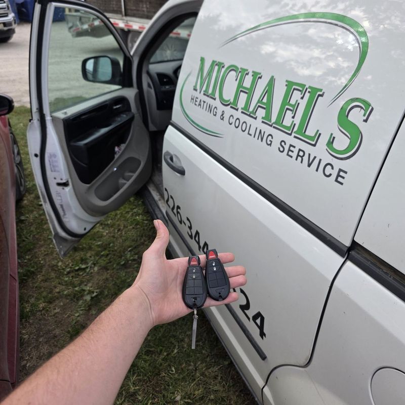 Two Dodge FOBIK keys held beside a lettered heating and cooling service van
